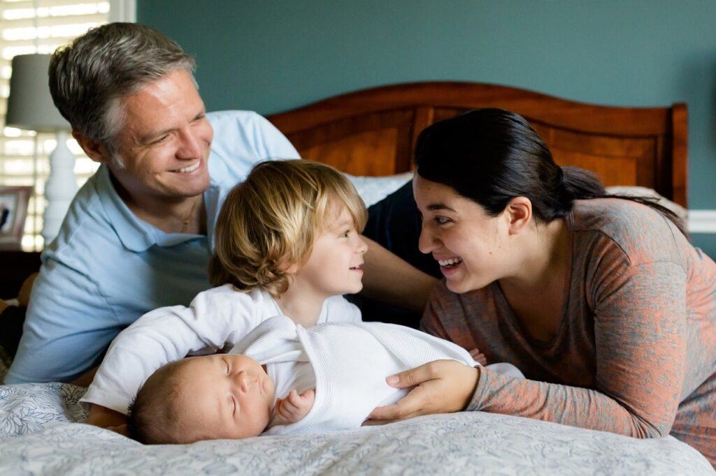 Happy family resting at the edge of a bed.