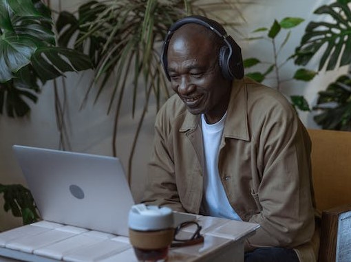 Older man drinking coffee, smiling (cause he's drinking coffee, right?), and working on a laptop.